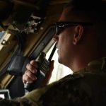 A pilot speaking on an aviation handheld radio in the cockpit