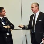 Two elderly pilots talking to each other at an airport
