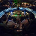 Two pilots sitting in a lit up cockpit