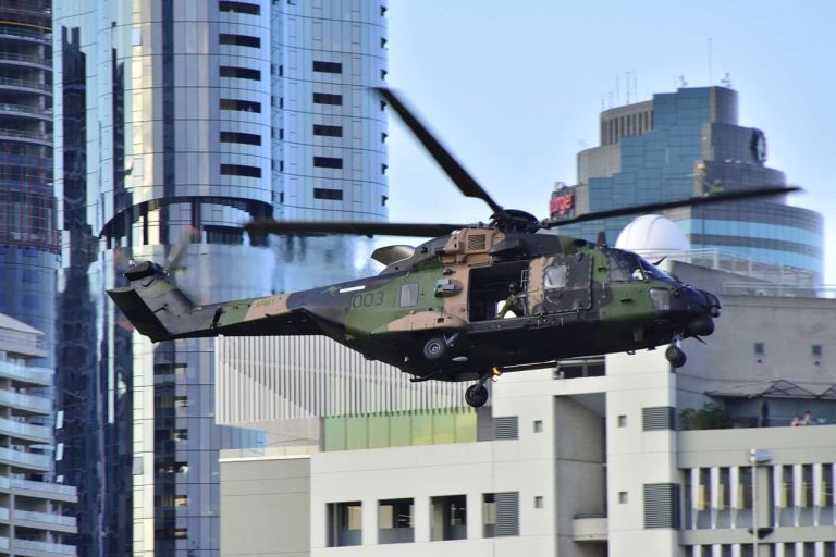 A military helicopter flying low over a city