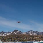 A helicopter flying over houses in a mountainous town