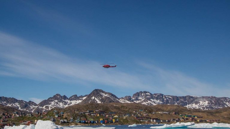 A helicopter flying over houses in a mountainous town