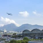 A commercial airliner climbing in altitude over a city