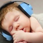 A baby wearing ear muffs as he sleeps