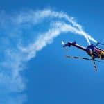 A helicopter flying upside down in blue skies