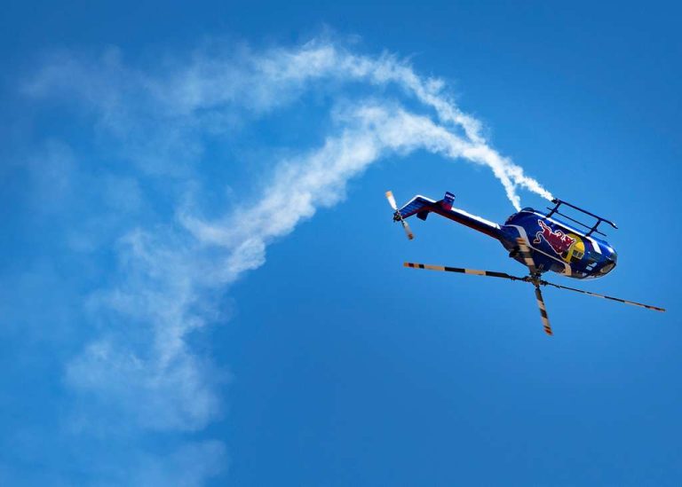 A helicopter flying upside down in blue skies