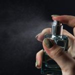 A woman spraying a bottle of perfume