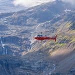6 Reasons Helicopters Are So Dangerous A red and white helicopter flying in a mountainous region