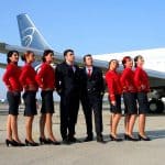 6 flight attendants standing next to two pilots