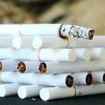 When Was Smoking Banned on Planes? (A Timeline) A lit cigarette resting on top of unlit cigarettes