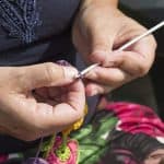 A woman crocheting and using crochet hooks