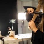 A woman straightening her hair in front of a mirror