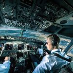 What is a First Officer on a Plane? (What It's Like to Be a Co-Pilot) A first officer with sunglassess piloting a commercial airliner
