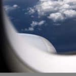 A view from a plane's window showing blue, cloudy skies