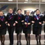 7 smiling female flight attendants with their arms linked