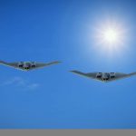 Two American stealh bombers flying side by side in blue skies