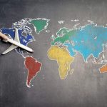 man holding a toy airplane over a world map