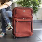 A man sitting at the airport with his suitcase next to him