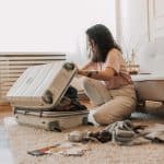 woman sitting on the floor packing her luggage