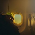 The Ultimate Guide to In-Flight Comfort man on a plane sitting by the window sleeping