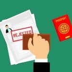 6 Most Common Travel Insurance Exclusions to Be Aware of A man stamping a travel insurance claim with rejected