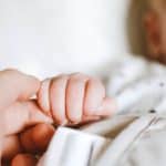 a baby clenching her mother's finger